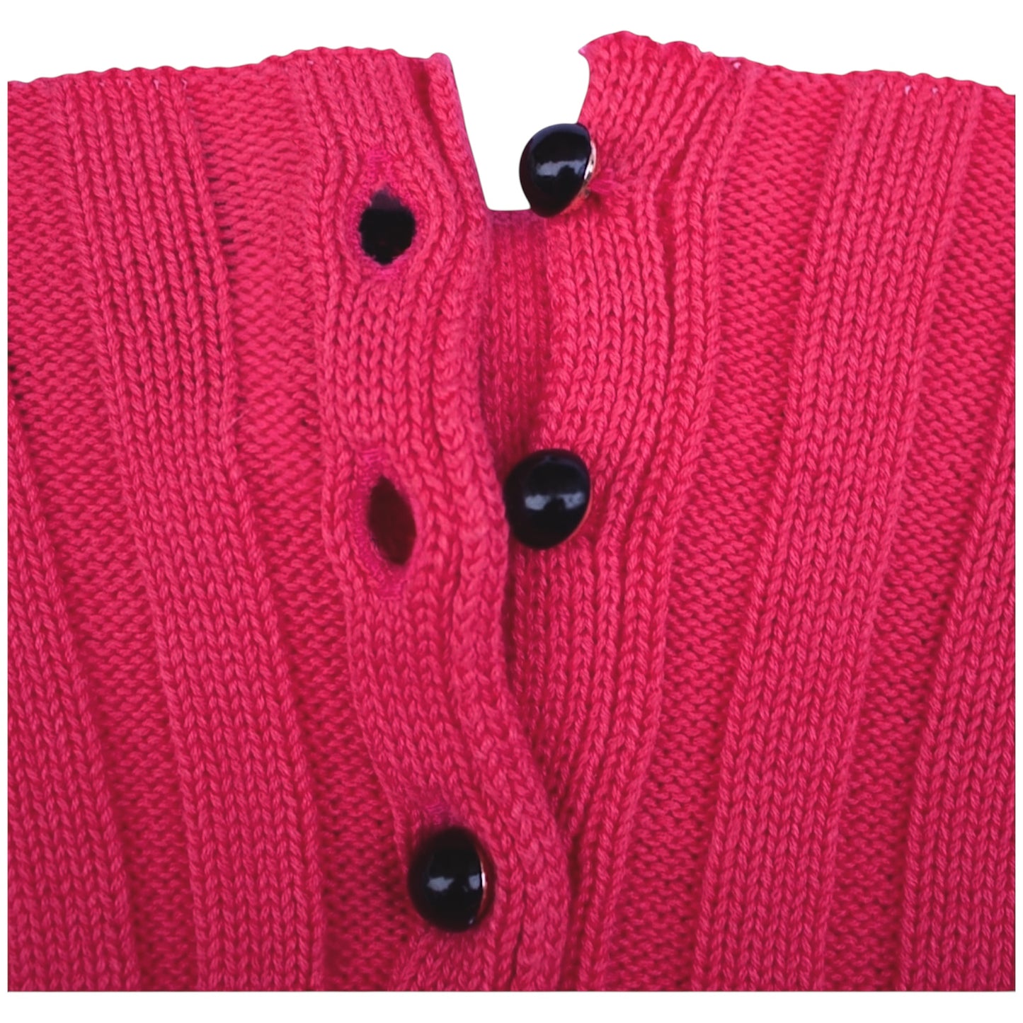 Close-up of a pink knitted garment with black buttons on a white background