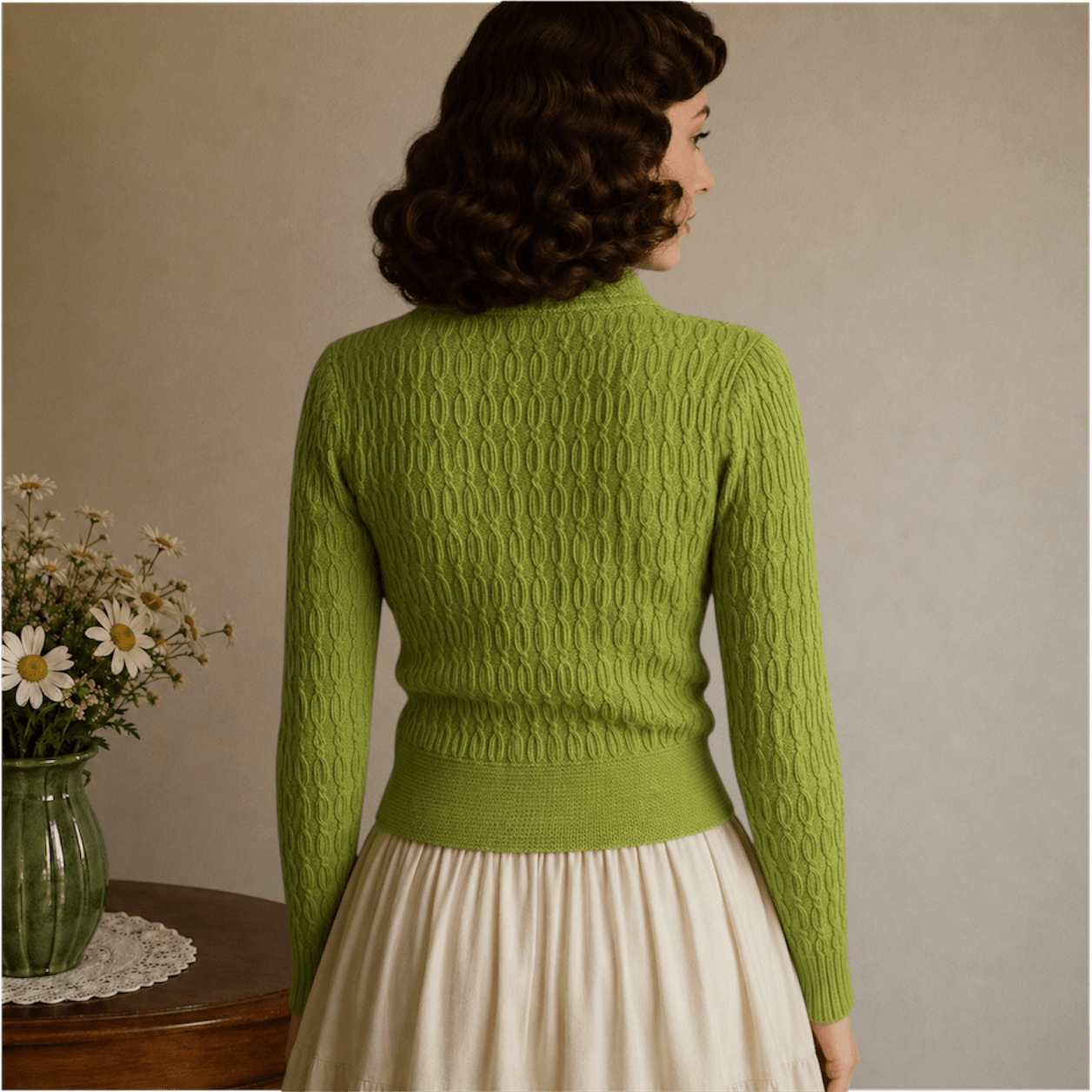 Woman wearing a green chunky cable knitted cardigan back view, vintage style with knit covered buttons 