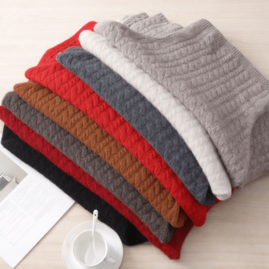 Stack of folded Chucky merino wool knit ponchos in various colours