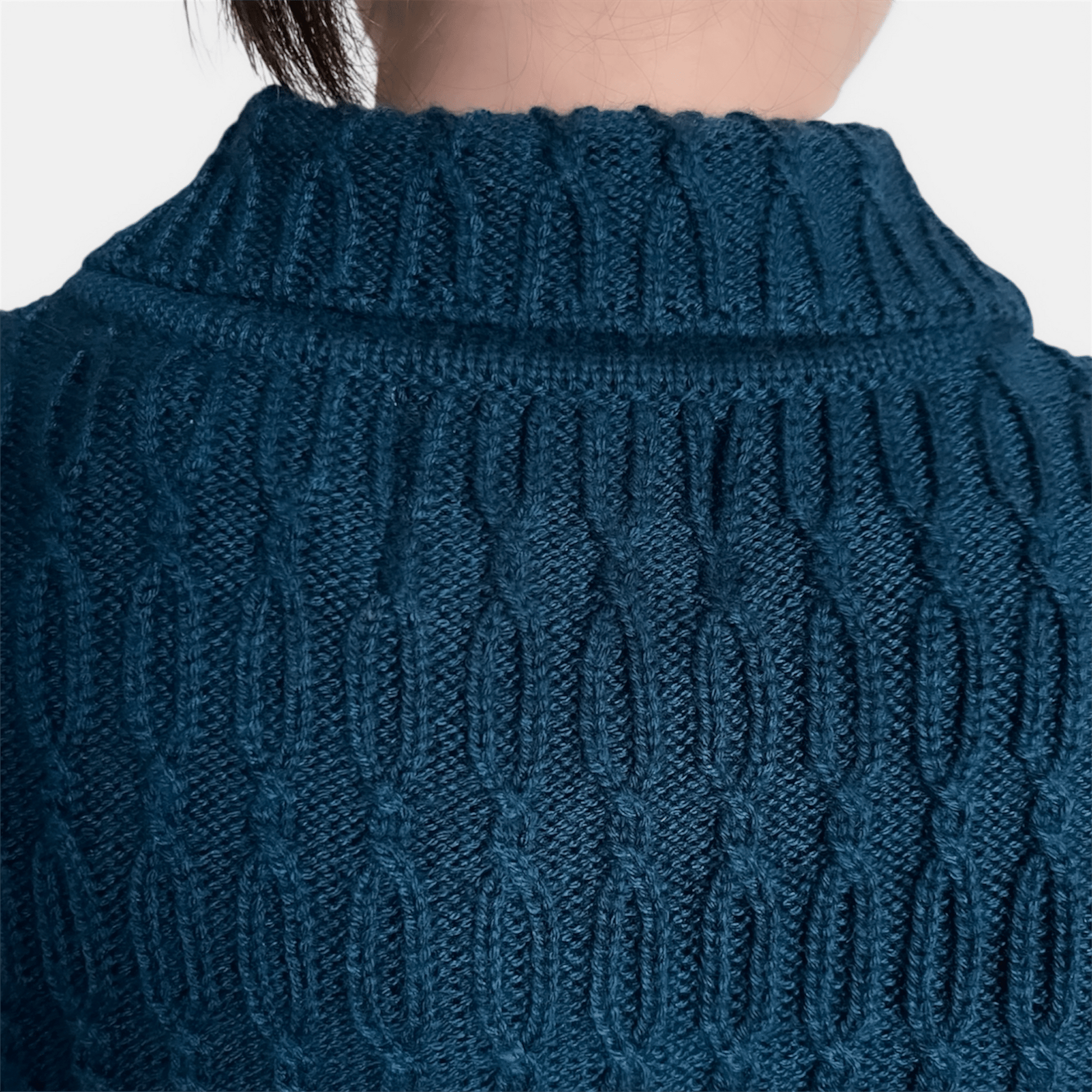 Close-up of a blue knitted sweater with a textured pattern on a white background