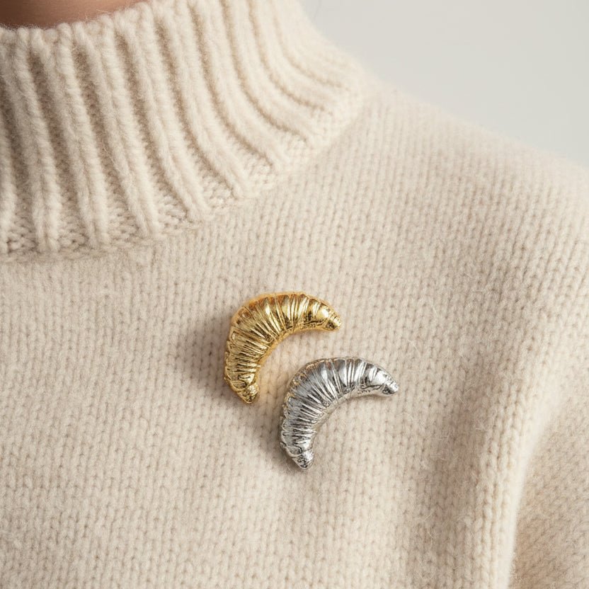 Gold and silver croissant brooches on a cream high neck chunky jumper 