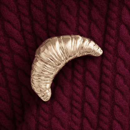 Light gold croissant brooch on chunky burgundy red knitwear 