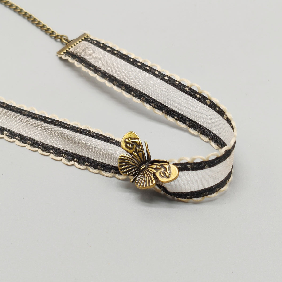 Ivory organza ribbon choker with antique bronze butterfly charm, product flat lay
