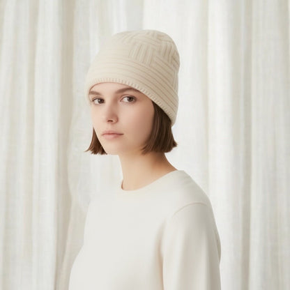 Person wearing a cream merino wool knitted beanie hat and a cream sweater 