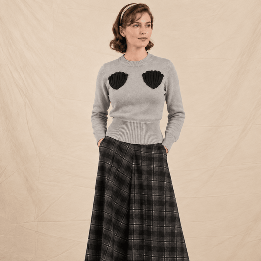 woman in grey jumper with black shell pockets styled with grey black check skirt
