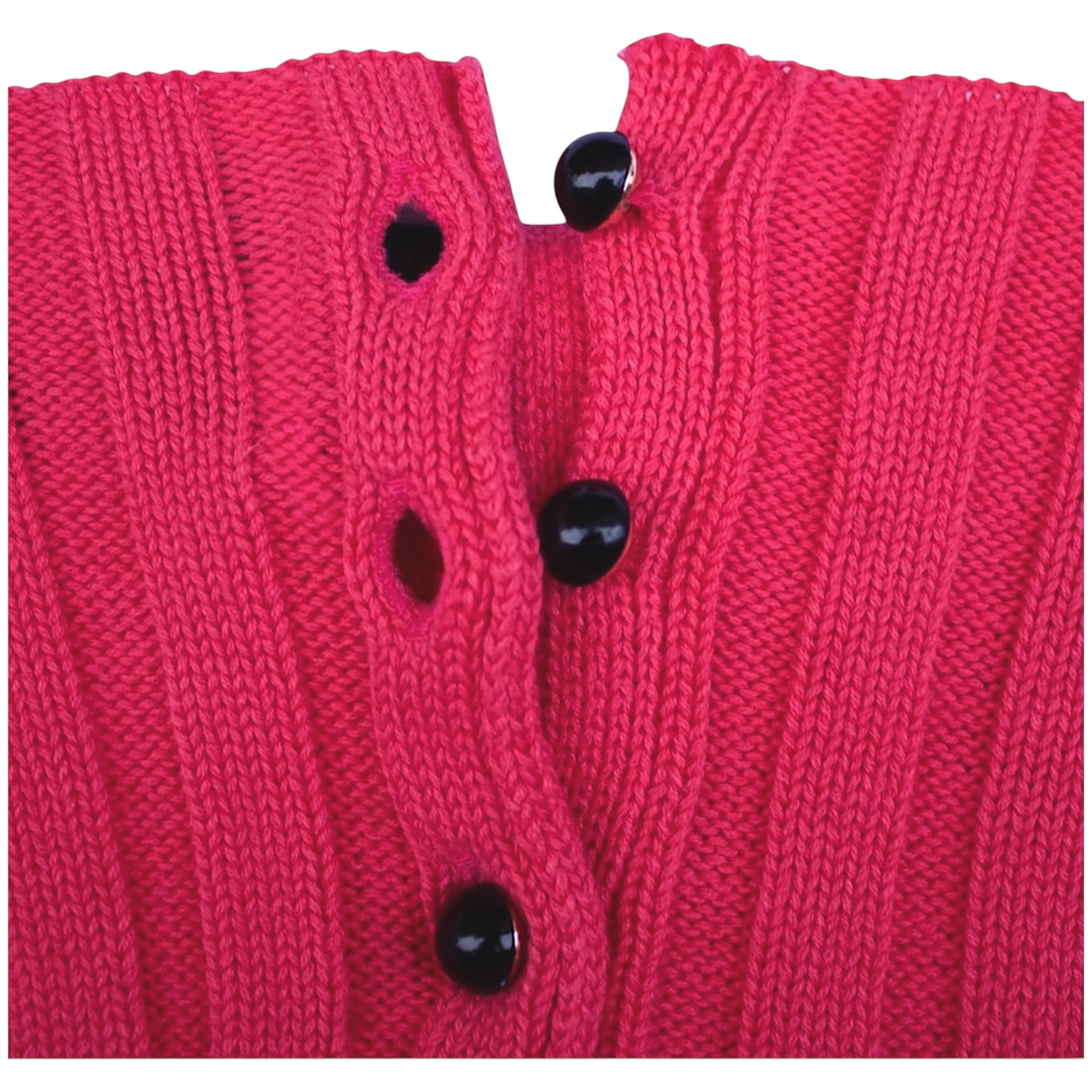 Close-up of a pink knitted garment with black buttons on a white background