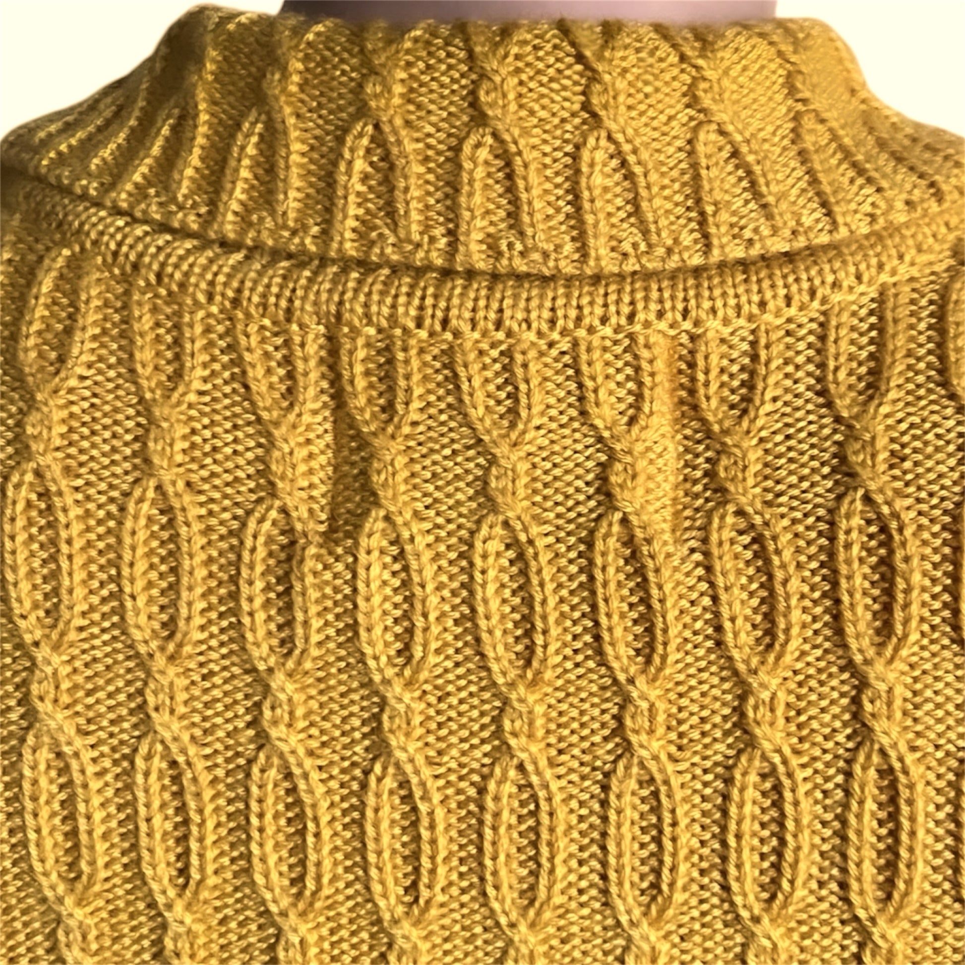 Close-up of a yellow knitted sweater with cable pattern