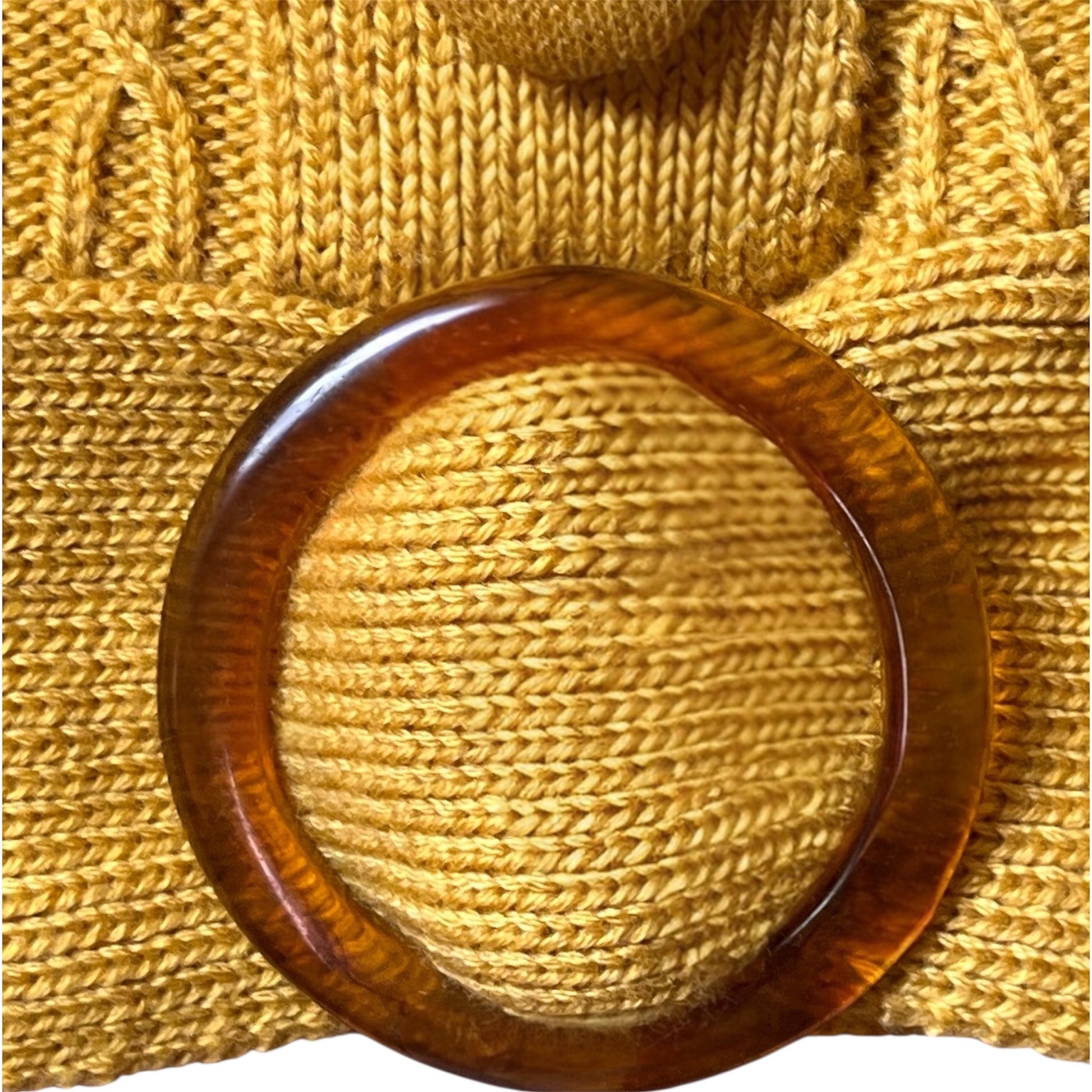 close up of an acrylic belt buckle on yellow mustard knit fabric