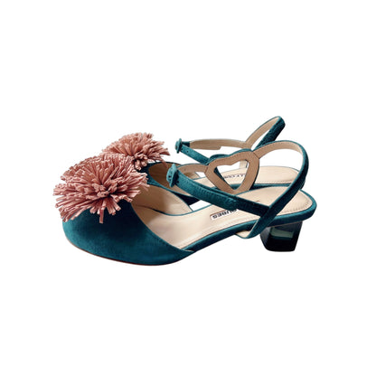 Side view of green suede pumps with decorative pom-poms and coloured crystal heels
