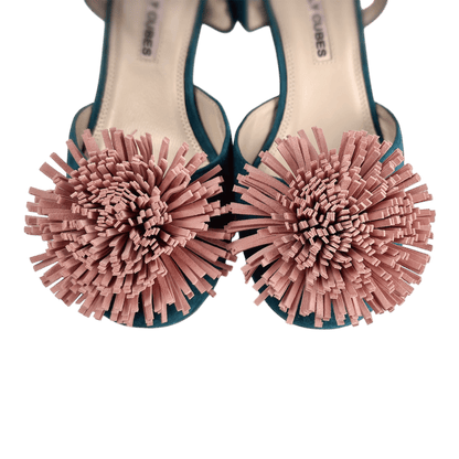 Decorative pom-pom embellishment detail on green suede Mary Jane shoes