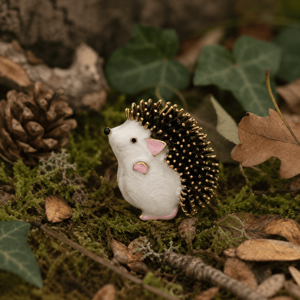 Woodland Hedgehog Enamel Brooch - front view on moss and autumn leaves