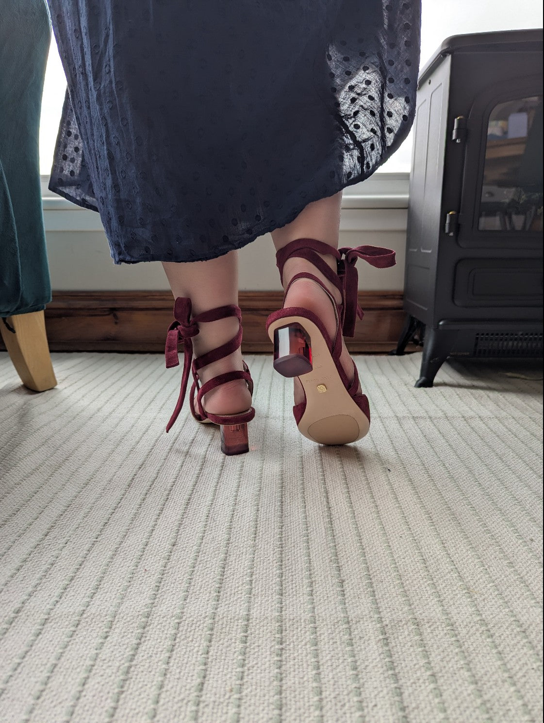 Person wearing red mid-heeled perspex shoes on a carpeted floor.