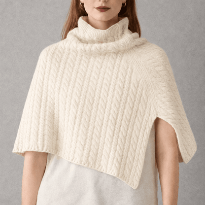 Model wearing a cream coloured cable knit  merino wool poncho 
