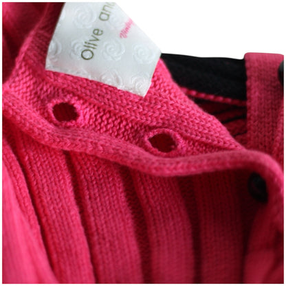 Close-up button holes of a pink knitted garment with a brand of olive and rose label 